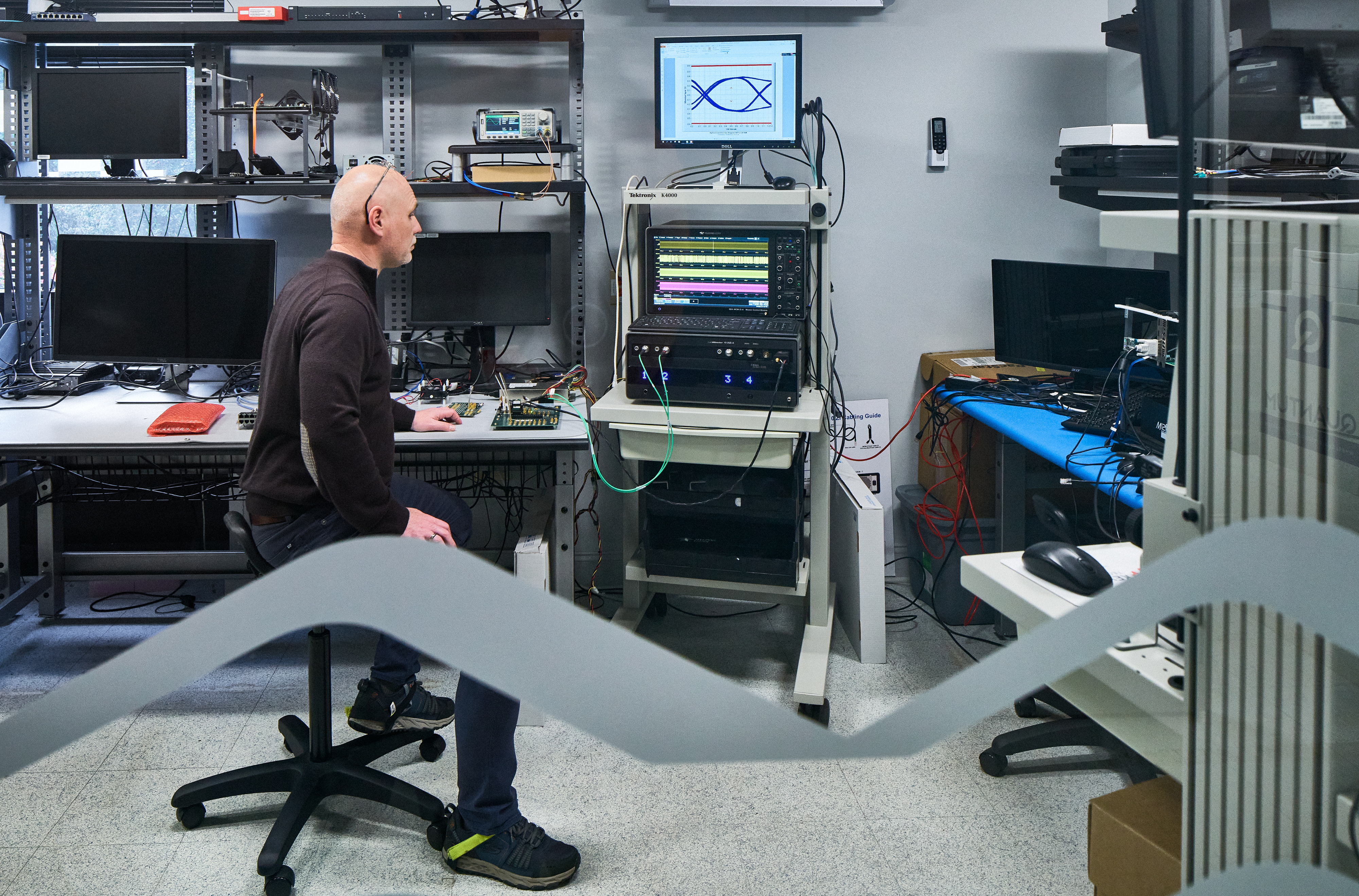 Sealevel Systems technician looking at computer monitors while testing components in a controlled lab environment.