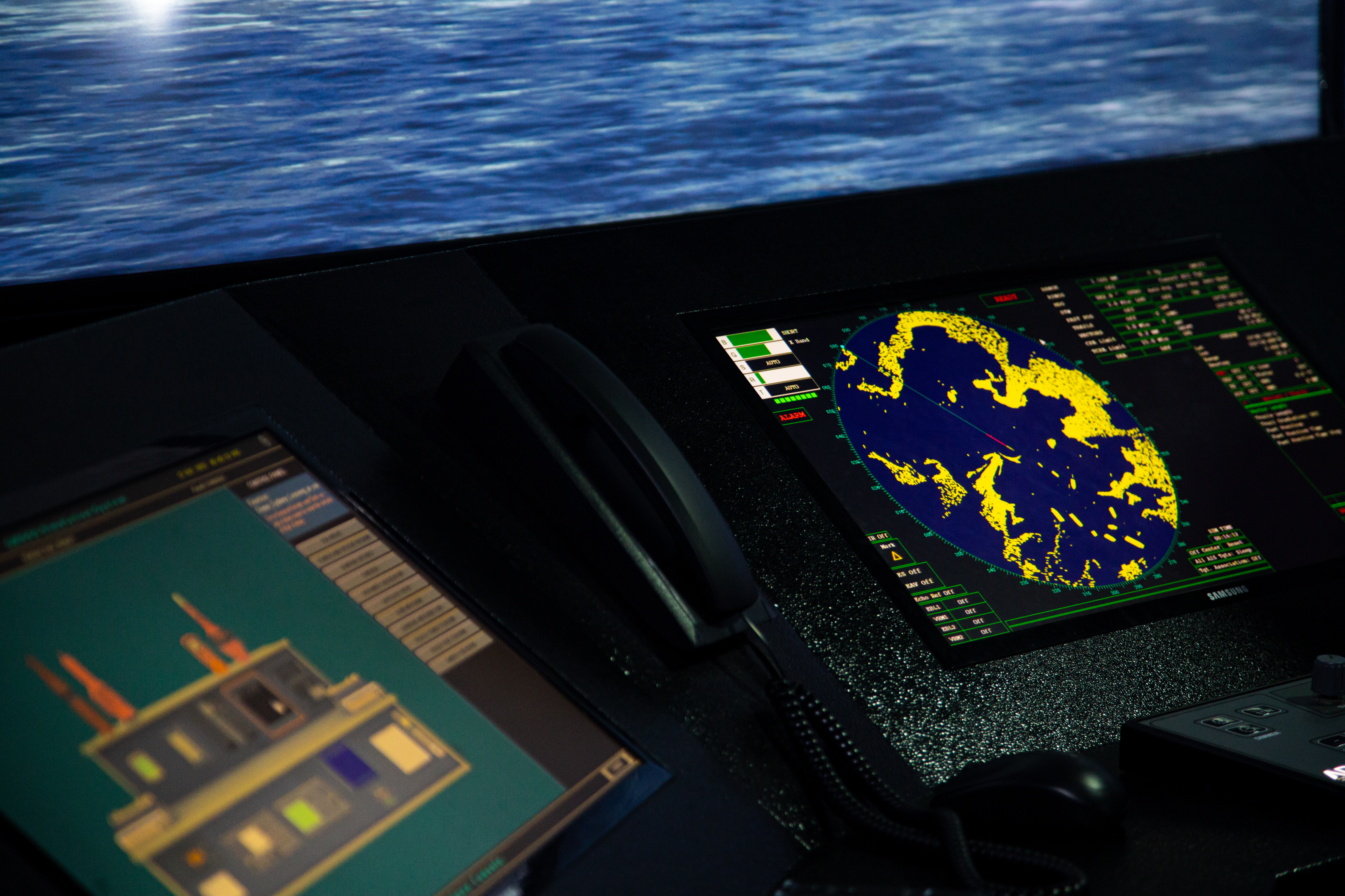 On-board display of radar and navigation screens. The ocean can be seen through the window.