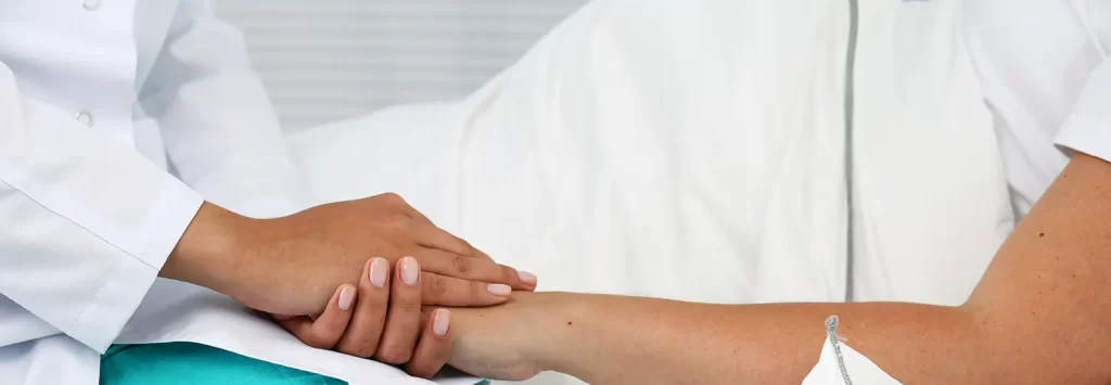 Friendly female medicine doctor hands holding pregnant woman's hand lying in bed for encouragement, empathy, cheering and support while medical examination