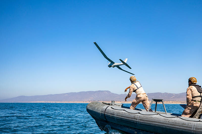 A soldier throws a drone off of a rhib to test new UAS system